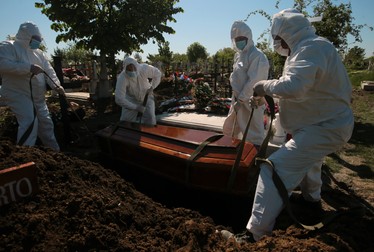 Groparii, în timp ce coboară în pământ un sicriu cu o victimă Covid
