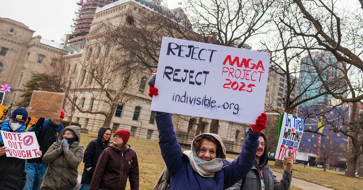 Un demonstrant ține o pancartă pe care scrie „Respingeți «proiectul MAGA 2025»”, în timpul unui protest anti-Trump la Reședința de Stat din Indiana, Indianapolis