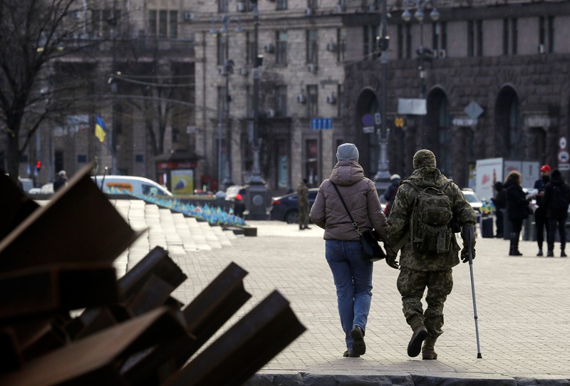 epa10483984 A woman an and injured soldier walk past Czech hedgehogs which were kept from the time as Russian troops were pushed back from the outskirts of the Ukrainian capital, on Independence Square in commemoration of fallen Ukrainian soldiers, in Kyiv, Ukraine, 22 February 2023. Russian troops on 24 February entered Ukrainian territory, starting a conflict that has provoked destruction and a humanitarian crisis. EPA-EFE/SERGEY DOLZHENKO