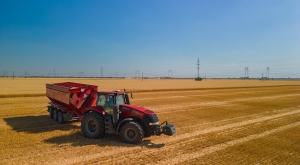 Un tractor roșu care a arat un lan de grâu și a strâns pe un câmp din România