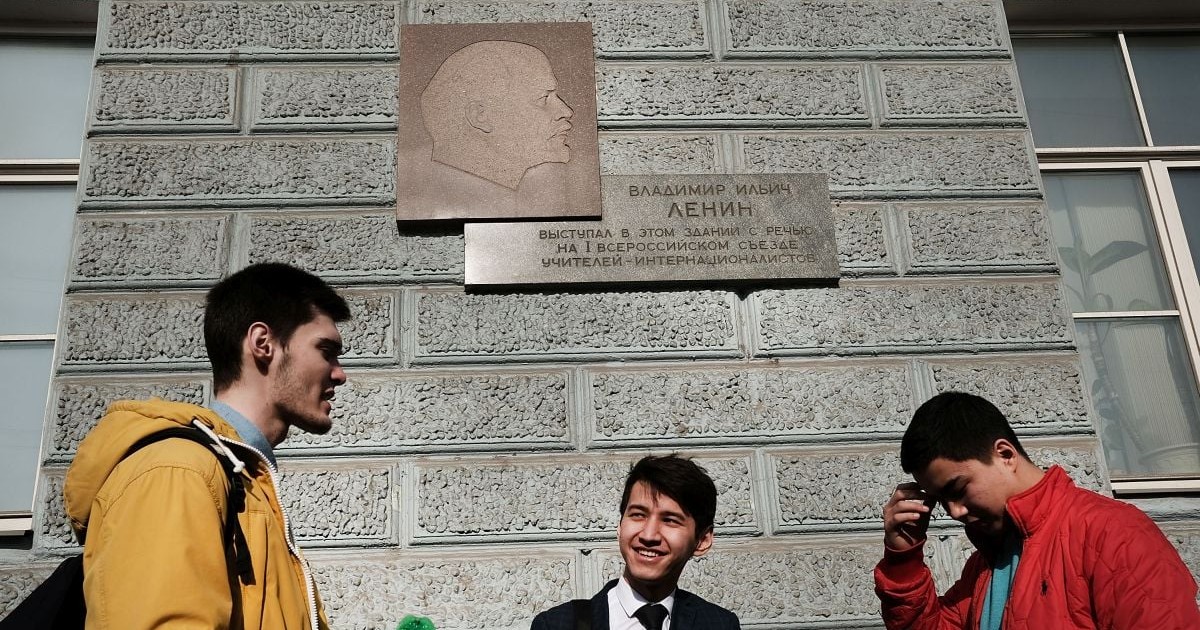 Trei studenți stau sub o placă memorială a lui Vladimir Lenin în centrul Moscovei, pe 9 martie 2017, la Moscova, Rusia.
