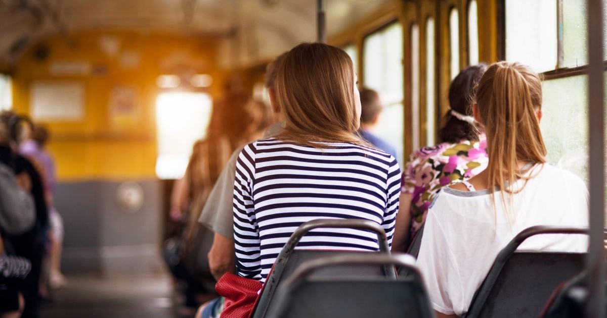 Mai mulți tineri sunt la o plimbare cu transportul public, în autobuz, la apusul soarelui