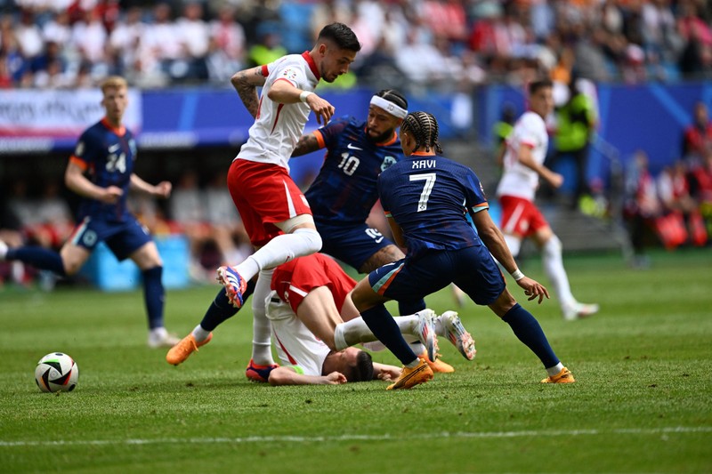 HAMBURG, GERMANY - JUNE 16: Xavi Simons (7) and Memphis Depay (10) of Netherlands in action against Piotr Zielinski (ground) of Poland during the 2024 European Football Championship (EURO 2024) Group D football match between Poland and Netherlands at Volksparkstadion Hamburg in Hamburg, Germany on June 16, 2024. Halil Sagirkaya / Anadolu/ABACAPRESS.COM