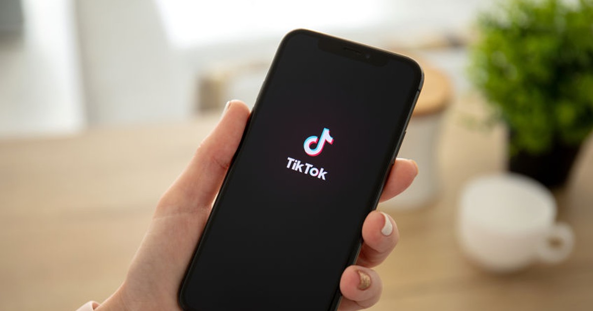 O femeie ține în mână un telefin pe care asteapta sa se deschida aplicatia TikTok