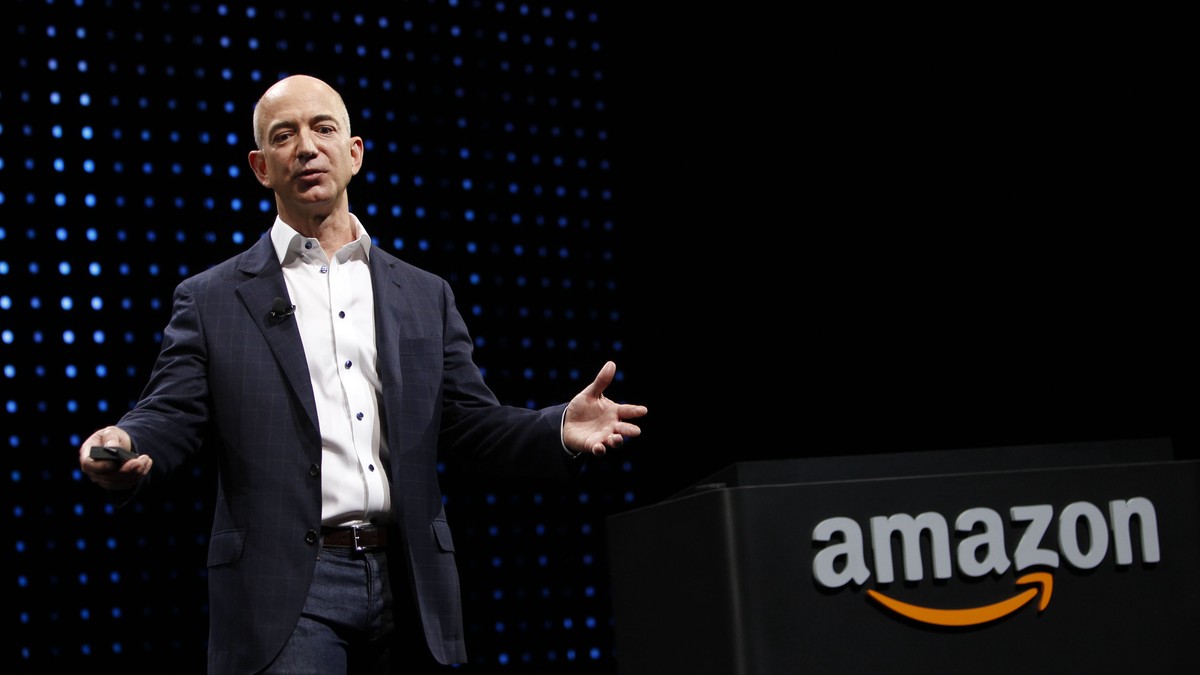 Jeff Bezos și Michael Bloomberg, printre cei mai mari donatori americani din 2020. Jeff Bezos în costum cu logo-ul Amazon în spate