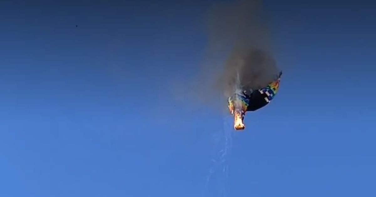 Un balon cu aer cald, cu coșul în flăcări, din care iese fum negru