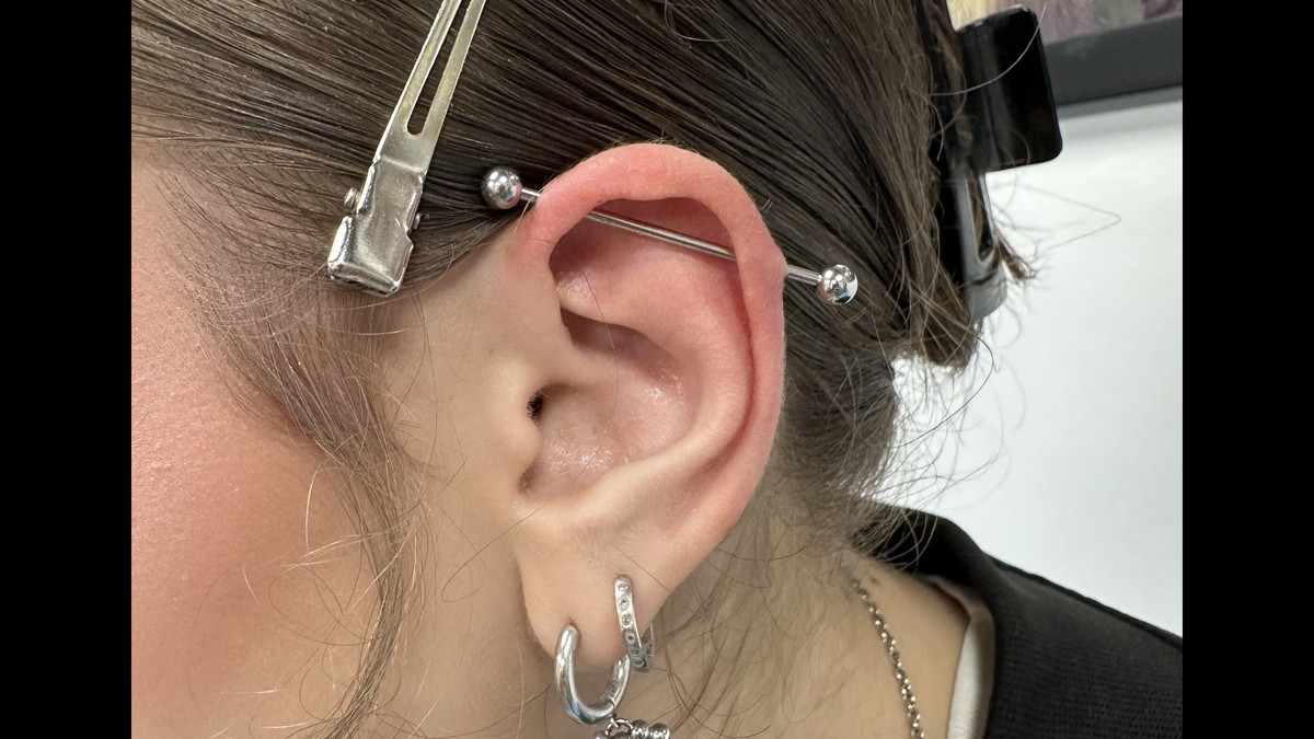 2nd Face Tattoo - poza cu urechea unei fete satene avand un piercing lung in partea superioara si doua piercinguri in partea de jos