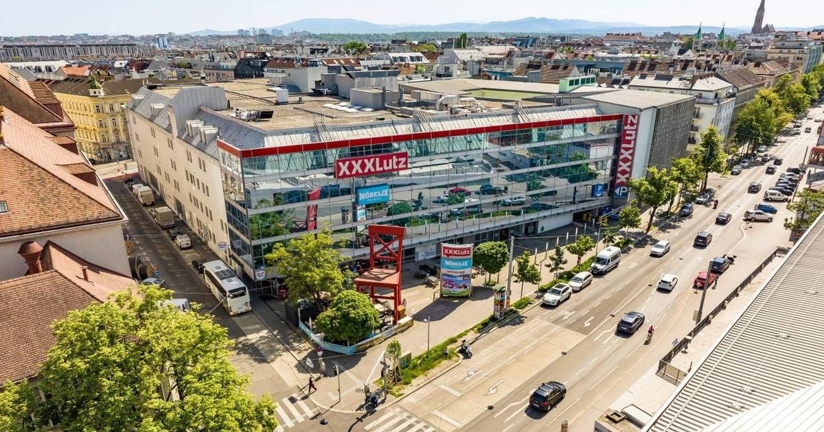 Imaginea prezintă o vedere aeriană a unui magazin de mobilier XXXLutz din Viena, situat la o intersecție circulată.