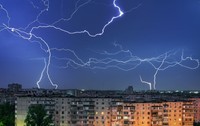 Furtună cu fulgere peste un oraș, cu blocuri în parte de jos a pozei, pe timp de noapte
