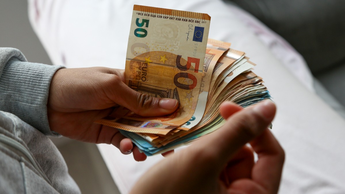 O femeie care ține în mână mai multe bancnote de euro.