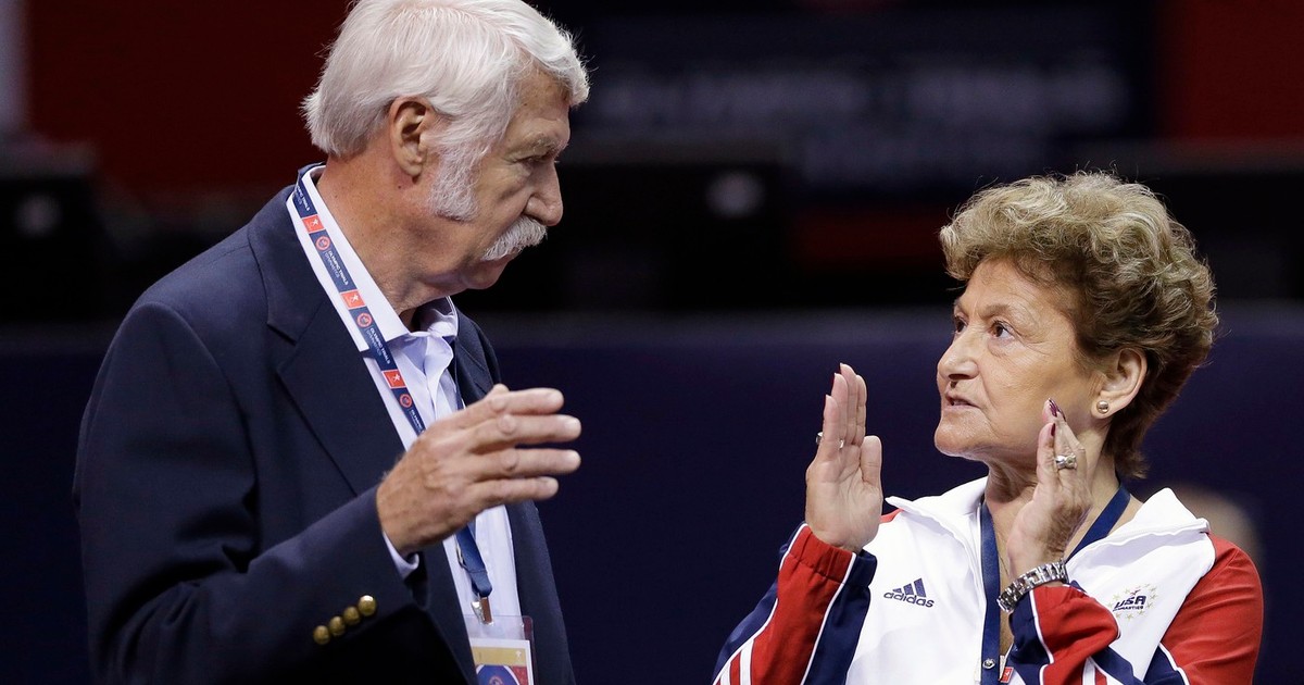 Bela Karolyi, stânga, și soția sa, Martha Karolyi, discută pe podeaua arenei înainte de începerea rundei preliminare a probelor feminine de gimnastică olimpică în San Jose, California.