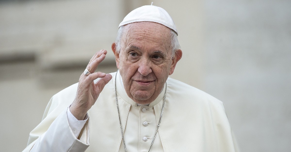 În imagine este ilustrat Papa Francisc, în timp ce ține mâna dreaptă ridicată