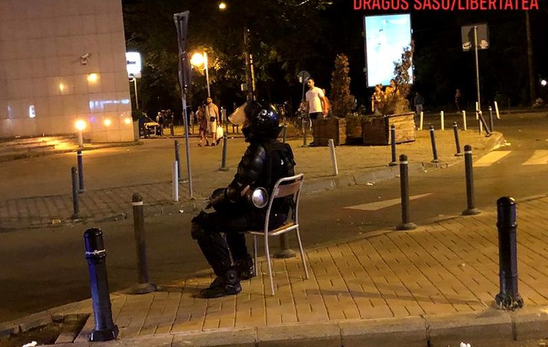 Povestea din spatele fotografiei virale cu jandarmul care stă pe un scaun, după intervenția din Piața Victoriei. Cum a fost realizată ”Cumințenia pământului”