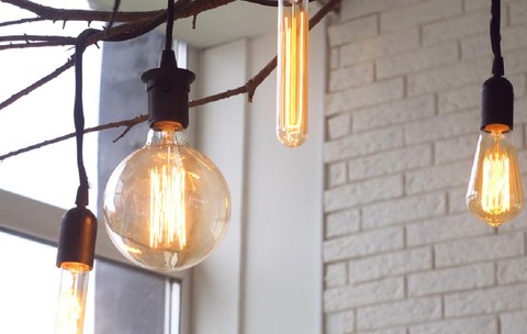 De ce pâlpâie sau rămân ușor aprinse becurile LED  după ce ai stins lumina  - Becuri decorative cu filament aprinse, suspendate de o cracă de copac într-un interior modern.