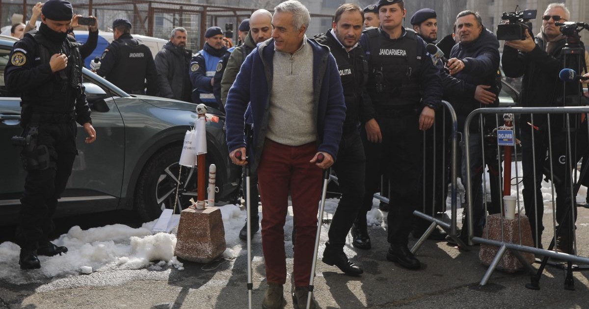 Călin Georgescu, îmbrăcat cu un pulover gri cu guler și un hanorac bleumarin, a fost surprins zâmbind când s-a dat jos din mașină, în fața Parchetului General