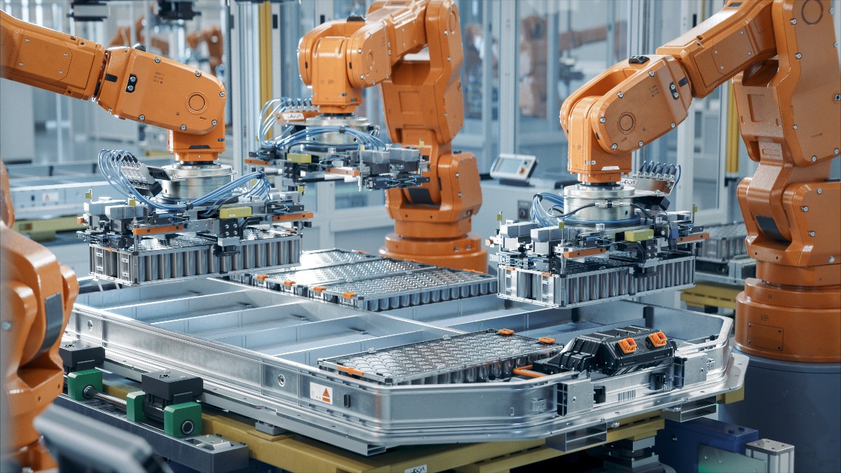 Imaginea prezintă o linie modernă și automatizată de producție a bateriilor pentru mașini electrice, în care mai multe brațe robotizate asamblează modulele. Fabrica este dotată cu echipamente industriale avansate, iar procesul de producție se desfășoară într-un mediu tehnologizat și organizat.