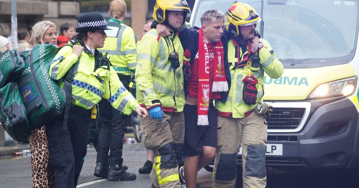 Mai multi suporteri ai echipei FC Liverpool au fost răniți după c eo masina a intrat in multime. In imagine vedem un cetatean ranit transportat de doi lucratori din serviciile de urgenta