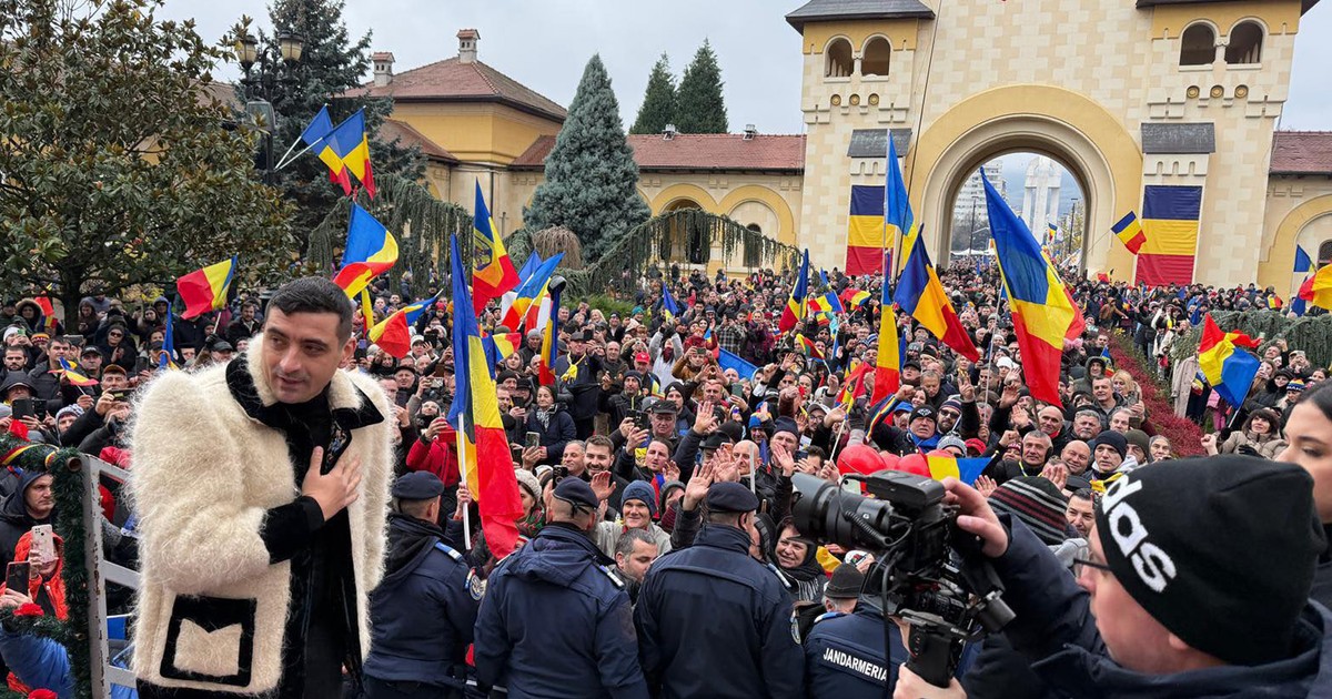 George Simion îmbrăcat într-o haină cu aspect tradițional în fața susținătirlor lui care flutură steaguri românești.