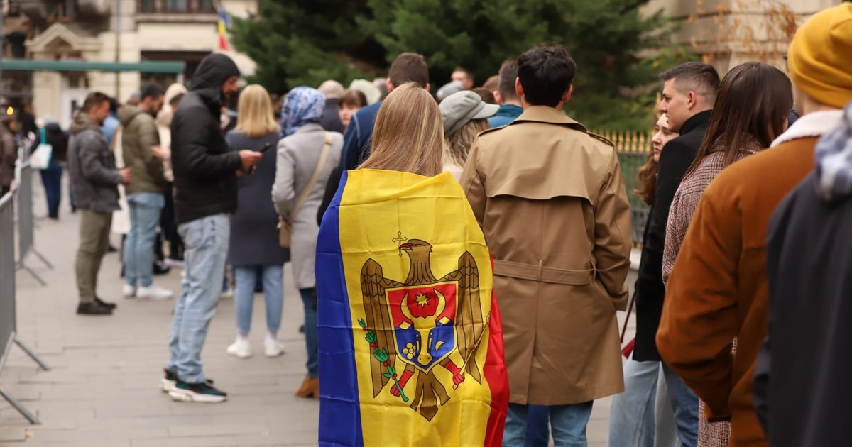 O tânără cu steagul Moldovei pe umeri așteaptă să voteze la o secție de votare din București