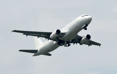 O fotografie a unui avion alb în zbor, care arată clar partea inferioară și motoarele pe fundalul unui cer albastru pal. Avionul este ușor înclinat în sus, surprinzând momentul ascensiunii.