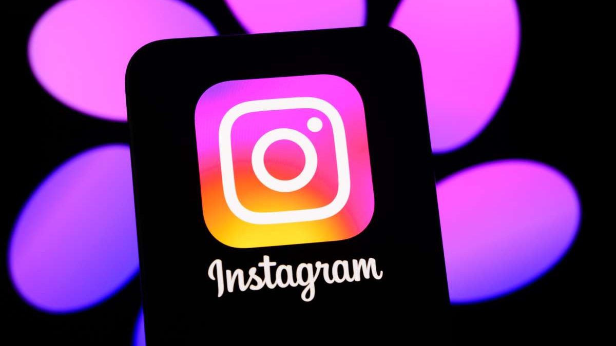 Logo-ul Instagram, afișat pe ecranul unui telefon, în fața unui fundal negru cu mov.