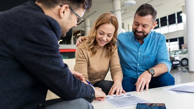 Mid-adult,Couple,Talking,With,Sales,Agent,And,Signing,Contract,For