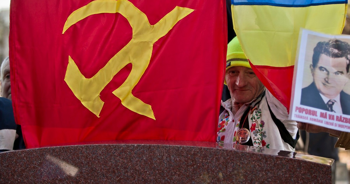 Un bărbat stă în spatele pietrei funerare a dictatorului comunist român Nicolae Ceaușescu, în timp ce nostalgicii comunismului se adună în jurul mormântului său din București, România, joi, 25 decembrie 2014, la 25 de ani după ce el și soția sa, Elena, au fost executați de pluton în ziua de Crăciun din 1989