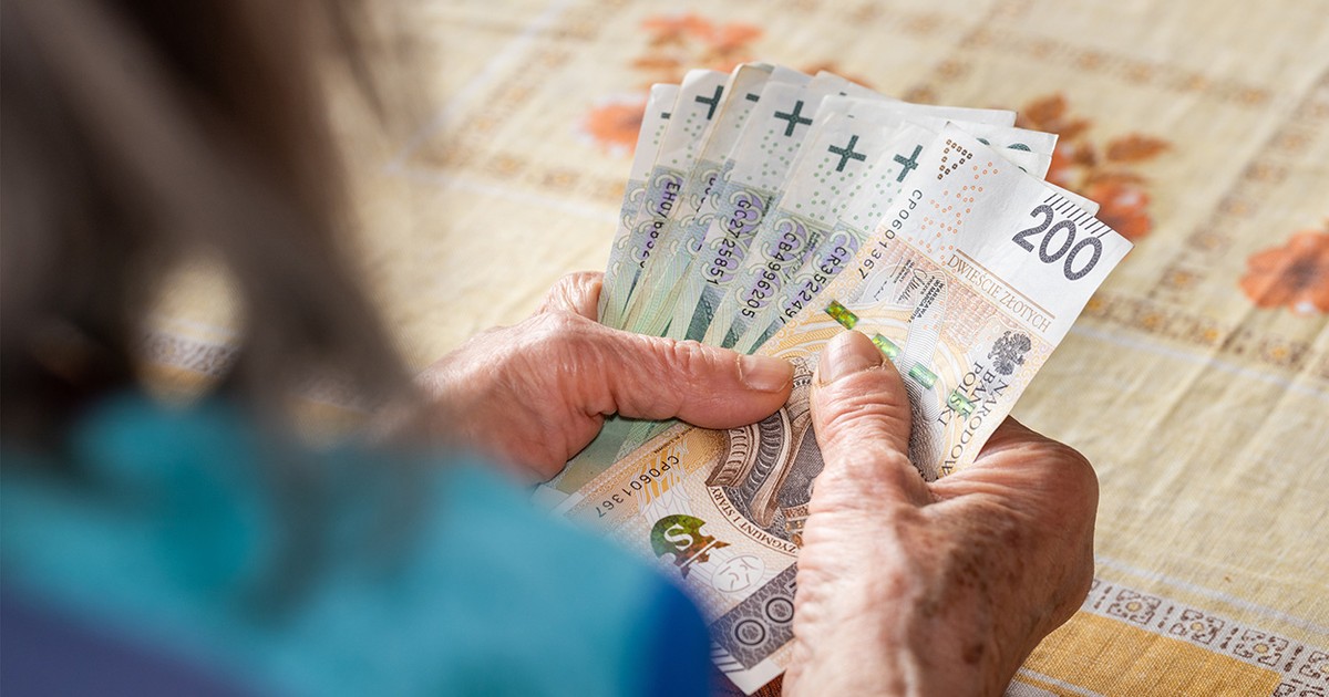 Mâinile unei femei căreia nu i se vede fața și care ține bani polonezi.