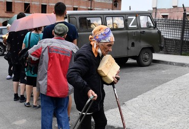Locuitorii stau la coadă pentru pâine la o stație mobilă de ajutor umanitar din apropierea bisericii de mijlocire din Mariupol, controlată de trupele pro-ruse. Foto: Profimedia