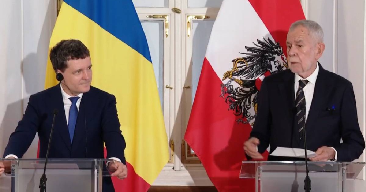Nicușor Dan îl privește pe Alexander Van der Bellen, cei doi președinți stau în fața unui pupitru, în timpul unei conferințe de presă