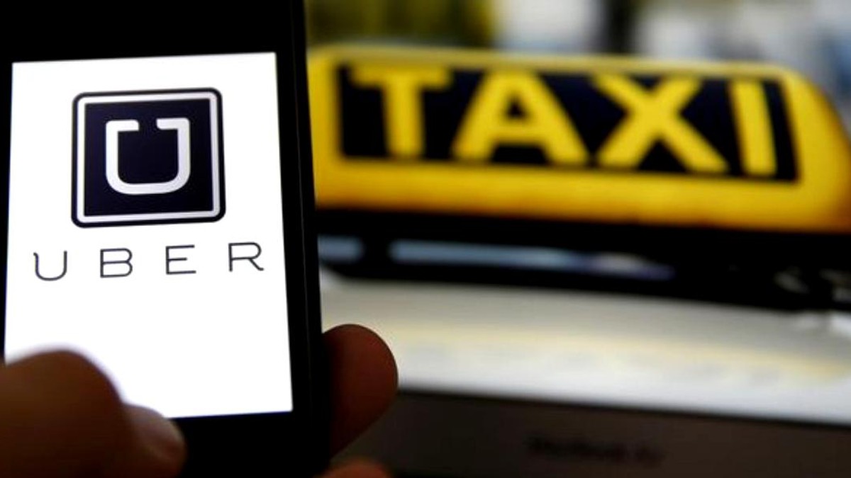 Uber a raportat pierderi de 1,1 miliarde de dolari pe ultimul trimestru din 2017. Aplicația Uber pe un smartphone cu un taxi în spate