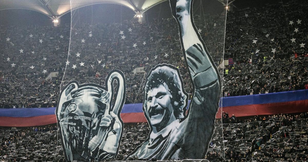 Suporteri pe un stadion de fotbal care au ridicat un banner cu Helmuth Duckadam și Cupa Campionilor Europeni câștigată de Steaua București în 1986