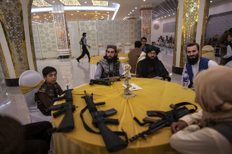 Taliban guards and guests sit at a table in the Imperial Continental wedding hall during a wedding in Kabul, Afghanistan, on Saturday, May 27, 2023. (AP Photo/Rodrigo Abd)
