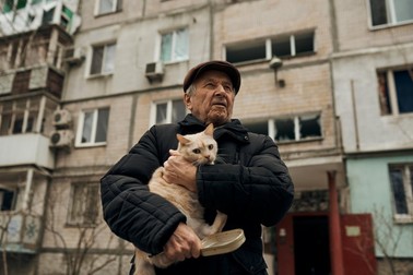 Un bărbat din Mikolaiv își protejează pisica de cioburile de pe stradă