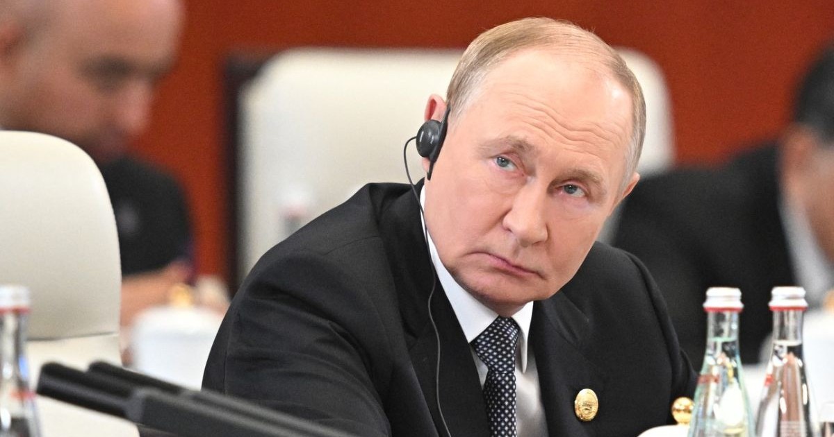 președintele Rusiei, Vladimir Putin, în sacou negru si cravata, cu o casca pe ureche si insigra in piept, asezat la masă la summitul Organizației de Cooperare de la Shanghai (SCO) de la Tianjin, pe 1 septembrie 2025