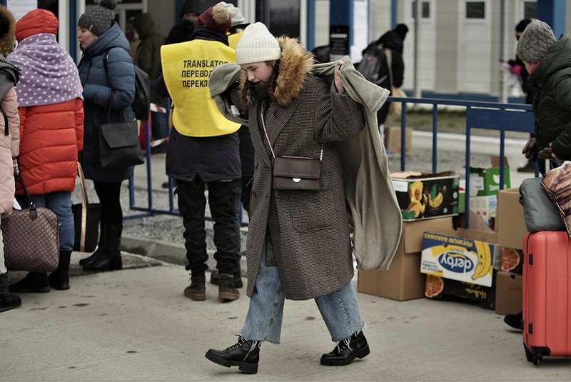 O tânără refugiată se acoperă cu o pătură luată din cutiile pregătite de voluntari