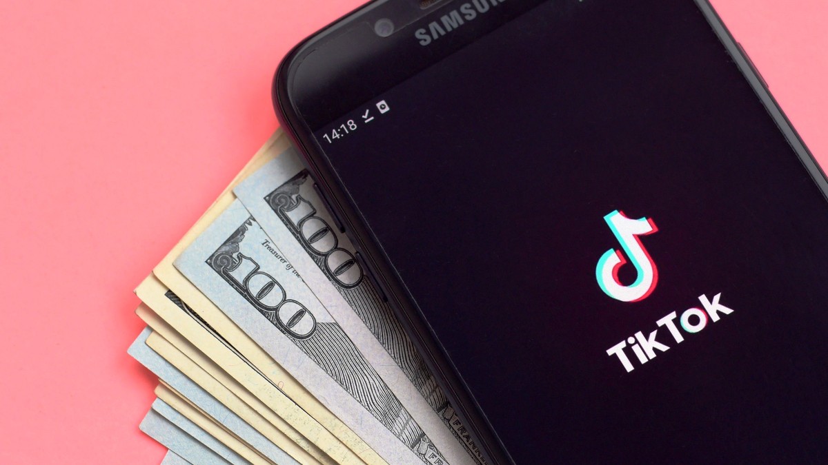 cum faci bani din TIkTok- un telefon cu sigla tiktok pe ecran asezat pe un teanc de bani