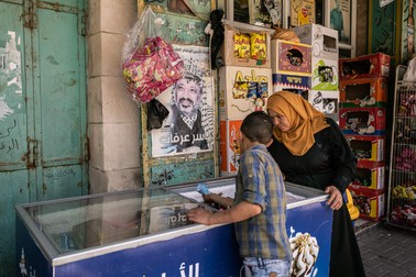 Un copil își cumpără înghețată de la un magazin din Hebron. În timpul zilei temperatura este foarte mare