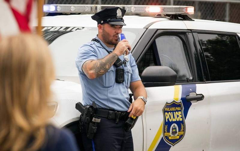 Un polițist din Philadelphia se sprijină pe mașina sa.