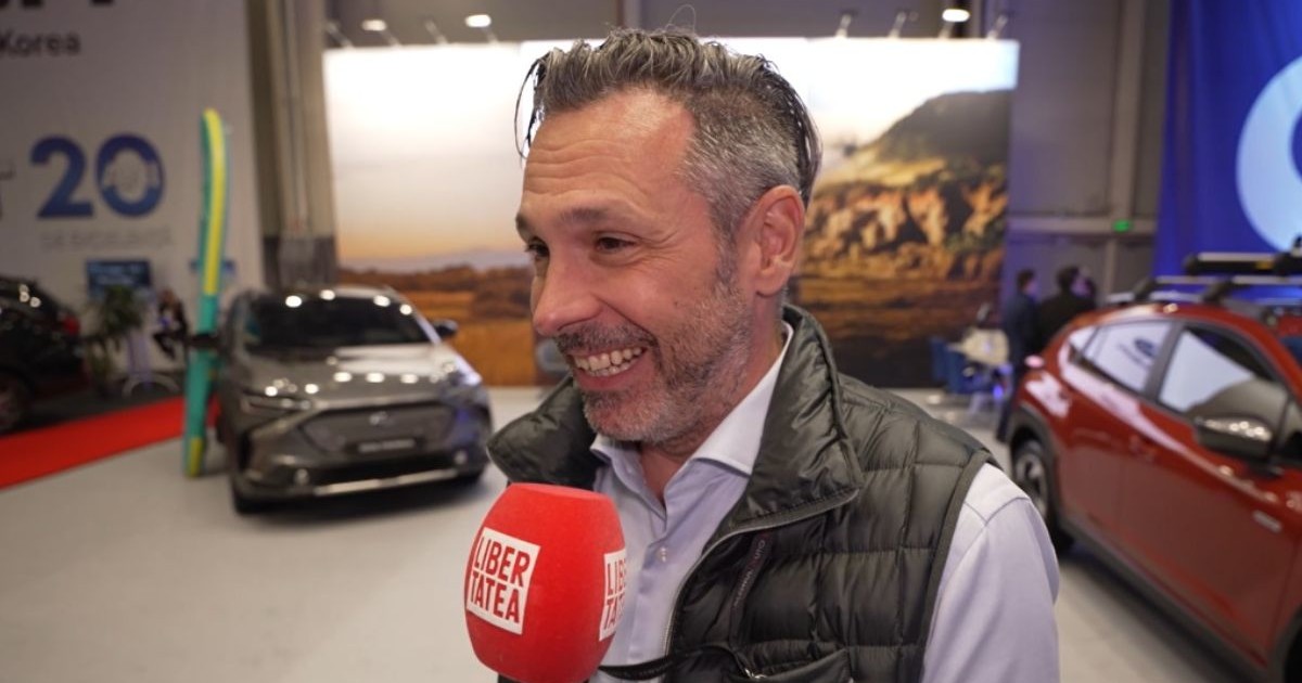 Albert Chiș, organizatorul Salonul Auto București 2025, îmbrăcat cu o cămașă deschisă la culoare și o vestă neagră deasupra, cu microfonul Libertatea în față