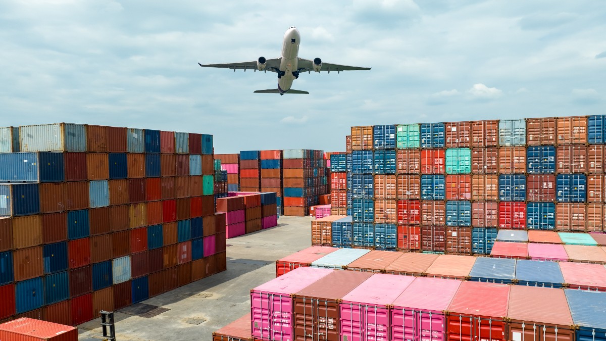 Mai multe containere de transport pentru colete Shein și Temu, sunt așezate într-un port, în timp ce un avion cargo trece pe deasupra lor