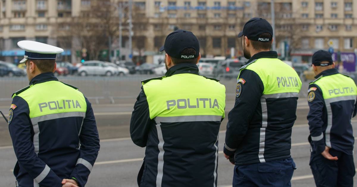 Patro ofiteri de politie, in uniforma bleumarin cu galben, cu scris pe spate POLITIA, in strada, toamna, in departare de vad masini in trafic, București, Romania, Piata Victoriei