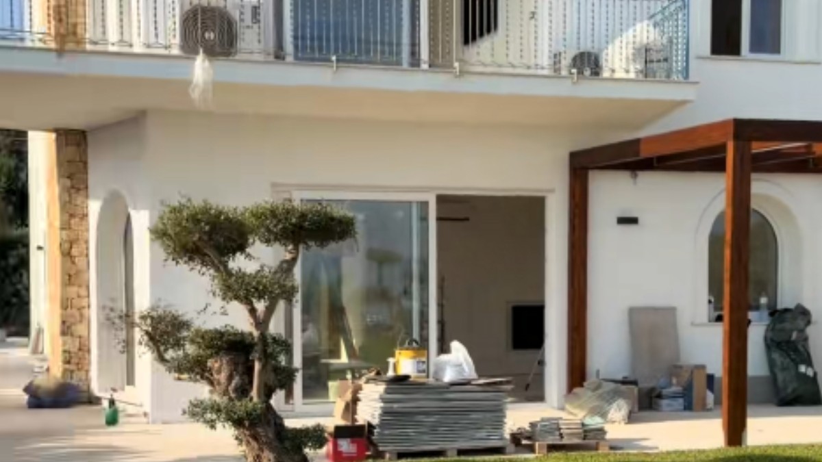 O casă albă lângă care se află materiale de construcție