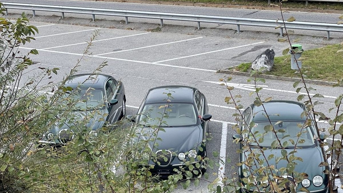 Trei mașini Jaguar S-Type de culoare verde-închis stau aliniate în parcarea popasului de pe autostrada Heidiland, una lângă alta, 2025