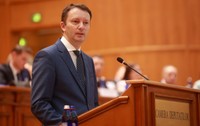 Europarlamentarul Siegfried Mureșan vorbind de la tribuna Parlamentului, îmbrăcat într-un costum albastru și cravată cu picățele.   