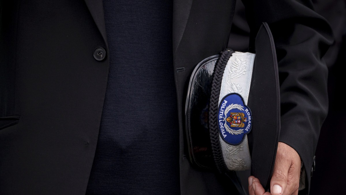 Polițist local, în timp ce își ține cascheta în mână