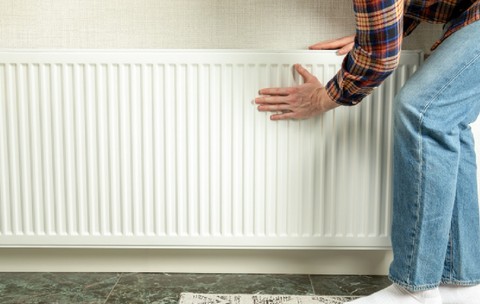 Persoana inspectează radiatorul pentru a se asigura că căldura este gata pentru sezonul de încălzire