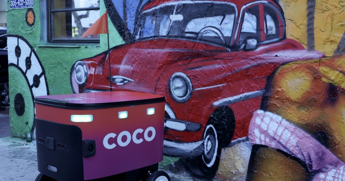 Un robot de livrare Coco Robotics stă lângă o pictură murală cu o mașină veche, lângă un restaurant, pe 22 iulie 2025, în Miami, Florida.