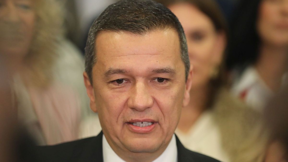 Sorin Grindeanu, ministrul Transporturilor, în prim plan, cu câțiva oameni în spate care apar blurați
