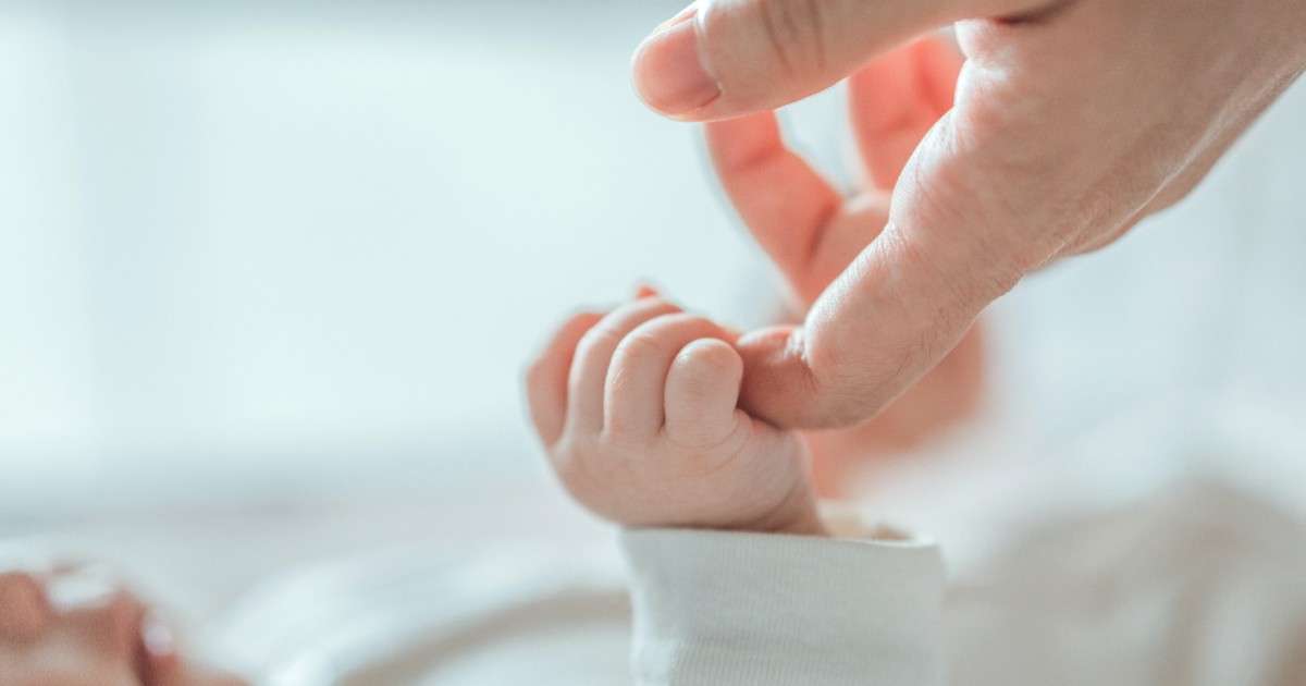 O femeie care ține mâna unui bebeluș.